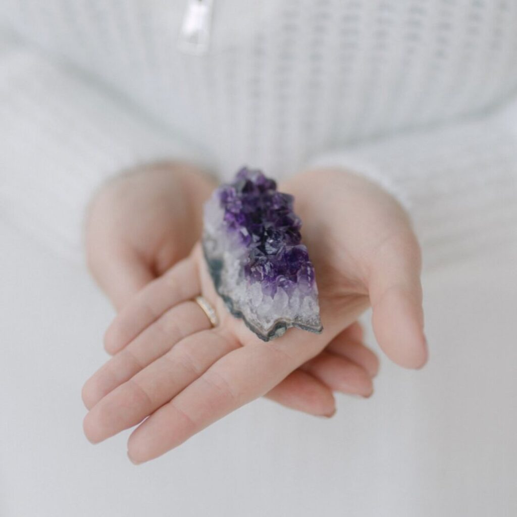 Amethyst-Kristall wird in Annas Hand präsentiert – Nahaufnahme